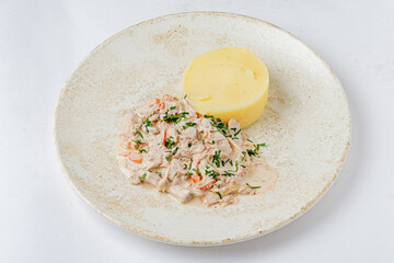 Creamy chicken dish topped with herbs, accompanied by smooth mashed potatoes on a rustic plate