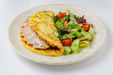 Mouthwatering chicken omelet paired with a vibrant salad of fresh greens and tomatoes