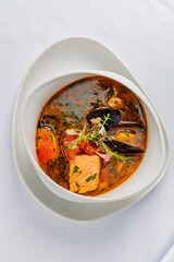 A warm bowl of seafood stew displaying fish, mussels, vegetables, and fresh herbs ready to savor