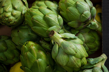 Obraz premium Bunches of bright green artichokes sit nestled with sunny lemons, showcasing nature's bounty