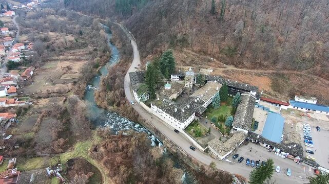 Drone video of the Troyan Monastery in March, showing the rooftops, the river, nearby nature and the winding road with cars. Smooth camera movement highlights the landscape, BG, EU, 02 Mach 2019