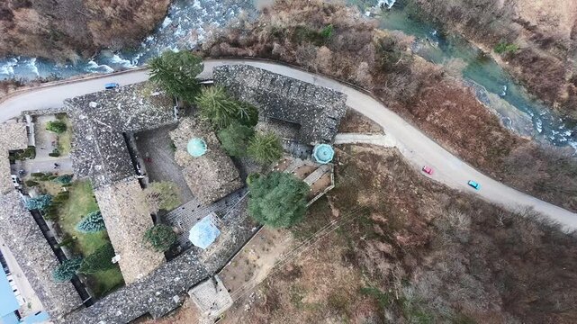 Drone video of the Troyan Monastery in March, showing the rooftops, the river, nearby nature and the winding road with cars. Smooth camera movement highlights the landscape, BG, EU, 02 Mach 2019