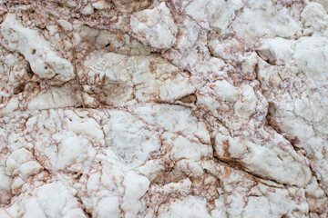 Natural cracked stone surface with intricate patterns and earthy colors. Perfect for backgrounds and design textures.