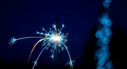 Sparkler with bright sparks on dark background, creating festive atmosphere. Light represents joy, celebration, and new beginning, perfect for event themes