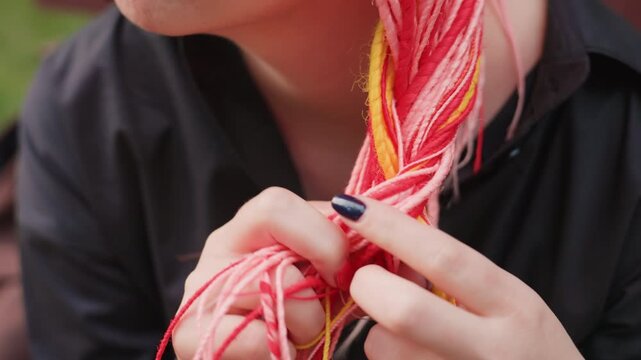 white woman touching bright braided hair near face, careful fingers and neon nails playing with strands, intimate closeup on texture and nervous energy, bench and park ambience in background