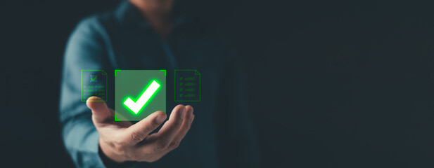 A businessman presenting a glow green checkmark symbol approval, completed tasks, and successful verification, ideal for concepts of quality assurance, validation, and digital workflow efficiency.