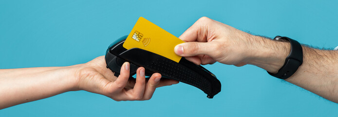 A hand holds a bright yellow contactless payment card while another hand reaches to accept it.