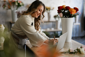 Florist woman writing orders in flower shop