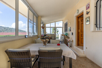 Fototapeta premium Enclosed terrace with wicker dining set and scenic mountain views