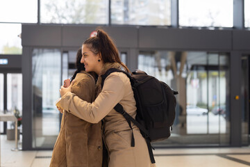Fototapeta premium Young woman traveler embracing friend at modern station