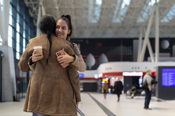 Young woman embracing friend at airport arrival