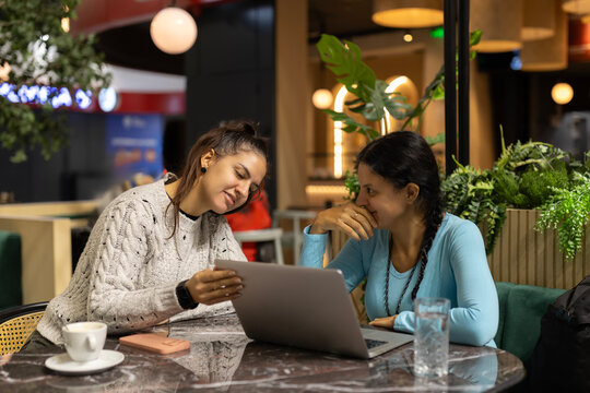 Young women collaborating on digital tablet in modern cafe