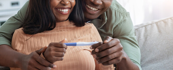 A couple shares a joyful moment at home, embracing each other while holding a pregnancy test. Their happy expressions reflect excitement and anticipation for new beginnings.