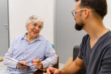 Senior woman discussing her medical records with male doctor during hospital visit for consultation
