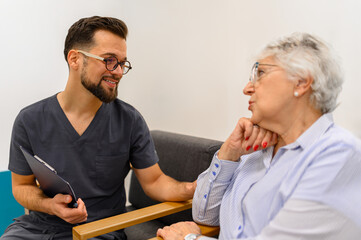 Male doctor touching worried senior woman's shoulder to comfort her during routine hospital health...