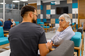Fototapeta premium Attentive senior woman listening to male ophthalmologist during her routine eye examination at hospital clinic
