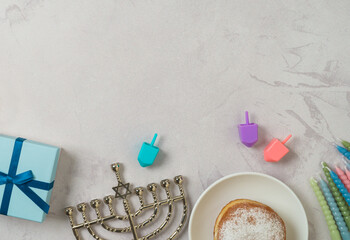 Jewish holiday Hanukkah concept with traditional donuts, menorah, colorful candles and gift box on bright background. Top view, flat lay