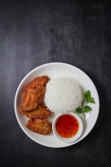 Fried chicken wings with rice and sweet chili sauce.