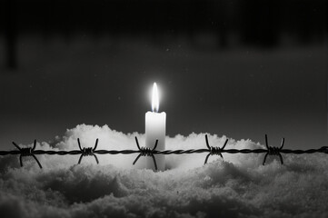Solemn remembrance concept for Holocaust victims. Candle and wire symbolizing history and memory.