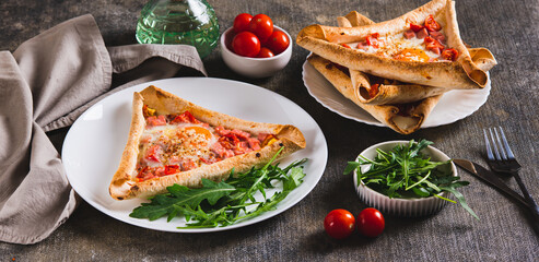 Egg, sausage and tomatoes baked in a triangular tortilla on a plate on the table web banner