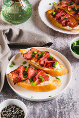 Baked bruschetta with ricotta and bacon on a plate on the table vertical view