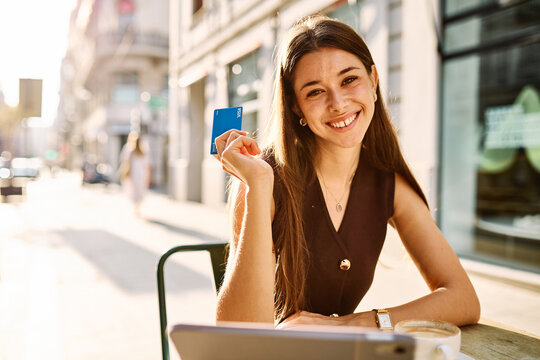 Portrait of a smiling young woman girl with a coffee cup in a coffee shop or a restaurant in the city, shopping online using a credit card and tablet online, or entrepreneur businesswoman working - Powered by Adobe