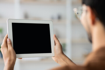 A person stands in a bright, organized workspace holding a blank tablet. They appear focused and are likely preparing for content creation or a digital presentation.