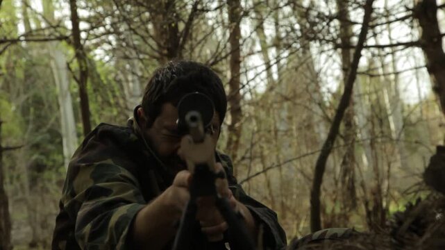 A focused sniper in camouflage uniform lies prone in a dense forest, aiming his rifle with precision while looking through the scope, ready for a crucial mission.