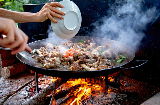 Traditional Valencian paella cooking process: adding crushed tomato to create the sofrito &ndash; Mediterranean cuisine in Spain.