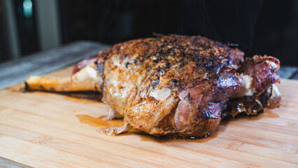 Whole roasted lamb leg with herb rub, golden brown crust, and aromatic seasoning on a wooden board. Juicy, tender, and ready to carve for a feast.