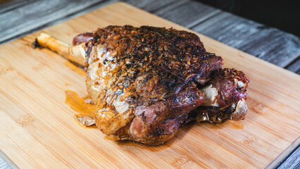 Whole roasted lamb leg with herb rub, golden brown crust, and aromatic seasoning on a wooden board. Juicy, tender, and ready to carve for a feast.