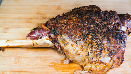 Whole roasted lamb leg with herb rub, golden brown crust, and aromatic seasoning on a wooden board. Juicy, tender, and ready to carve for a feast.