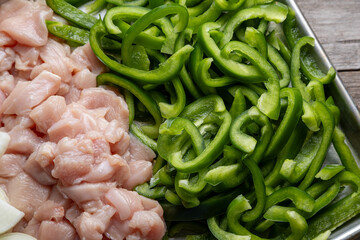 Sheet pan chicken fajitas with sliced onions, green bell peppers, and seasoned chicken arranged on a baking tray. Fresh, simple, and perfect for meal prep or easy dinner recipes.