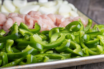 Sheet pan chicken fajitas with sliced onions, green bell peppers, and seasoned chicken arranged on a baking tray. Fresh, simple, and perfect for meal prep or easy dinner recipes.