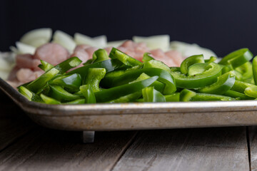 Sheet pan chicken fajitas with sliced onions, green bell peppers, and seasoned chicken arranged on a baking tray. Fresh, simple, and perfect for meal prep or easy dinner recipes.