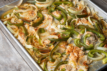 Sheet pan chicken fajitas with sliced onions, green bell peppers, and seasoned chicken arranged on a baking tray. Fresh, simple, and perfect for meal prep or easy dinner recipes.