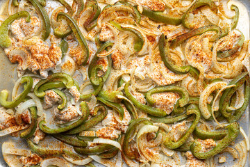 Sheet pan chicken fajitas with sliced onions, green bell peppers, and seasoned chicken arranged on a baking tray. Fresh, simple, and perfect for meal prep or easy dinner recipes.