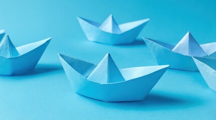 Delicate blue paper boats arranged on a soft blue backdrop evoke a sense of whimsy and creativity.