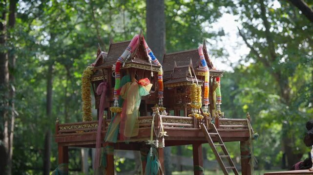 Cinematic footage of a sacred Mae Takian shrine located in a forest in Thailand.The video features detailed shots of a wooden spirit house, and the mystery of spirits or ghosts associated with worship