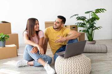 Two people sit on the floor of a bright room surrounded by moving boxes. They are smiling and talking, working together to settle into their new home.