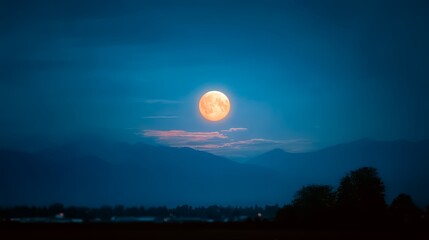 Fototapeta premium Large, bright moon is rising over a mountain range. The sky is dark. The scene is peaceful and serene