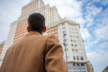 Man gazing at historic city building under a bright sky in the heart of the city
