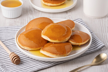 Delicious fluffy pancakes with syrup served on a white plate for breakfast
