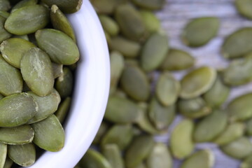 Pumpkin seeds in a wooden bowl on a wooden background