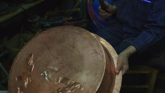 Turkish craftsman hammering a traditional copper cauldron