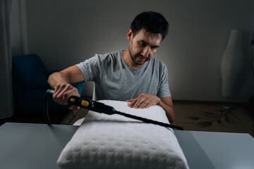 Cleaning service employee performing household chore, steam cleaning and sanitizing pillow, ensuring hygiene, purity and disinfection in bedroom, promoting health and wellness through deep cleaning.