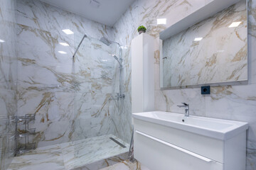 The modern bathroom is decorated with marble tiles, with a spacious shower cabin and a stylish...