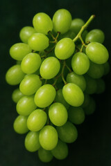A vibrant bunch of green grapes, glowing against a dark background, embodies freshness and the simple pleasure of fresh, natural snacks.