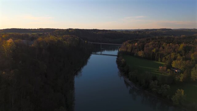 Aerial view of a high new bridge over the Inn River near Wasserburg am Inn, Germany, Bavaria. Spring sunset lights valley and forests, highlighting tranquil river scenery and scenic Bavarian nature