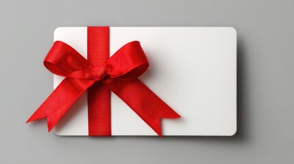 A simple elegant gift card wrapped in a vibrant red ribbon sits on a smooth gray surface. Ideal for birthdays and celebrations it embodies joy and generosity.